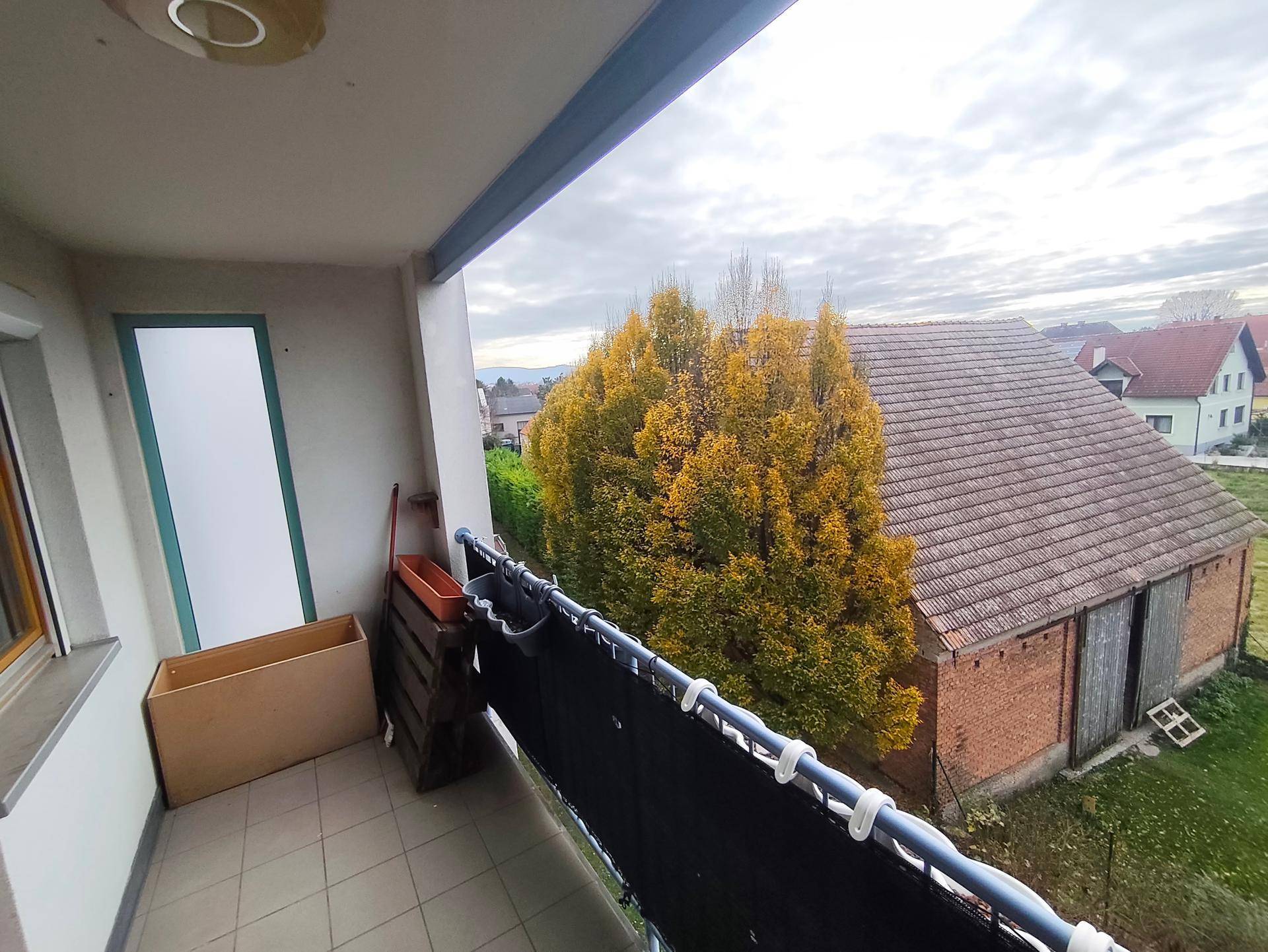 Balkon mit Blick auf ein Gebäude und herbstliche Bäume in der Umgebung.