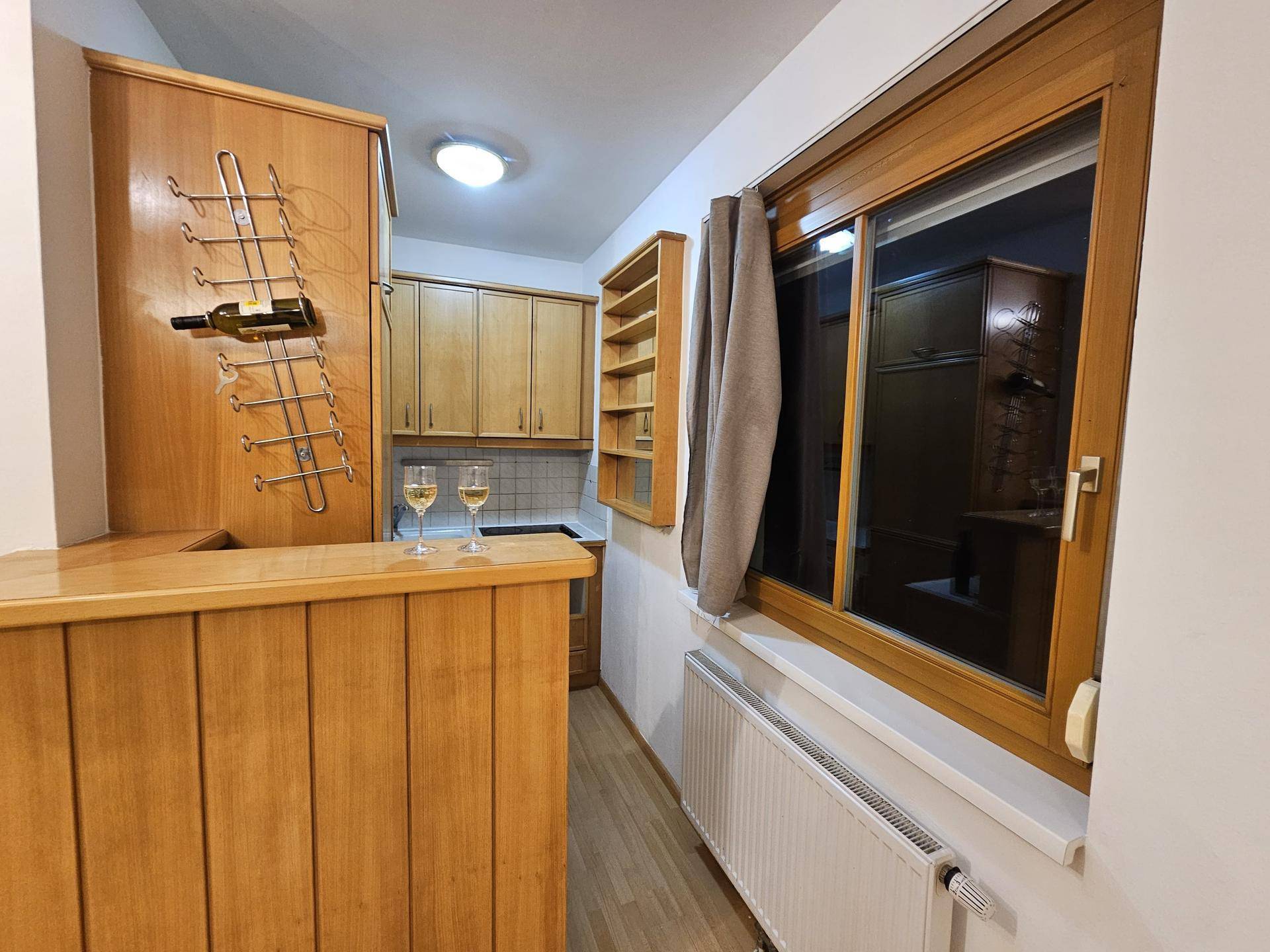 Küche mit Holzschränken, Fenster und Heizkörper, bietet eine gemütliche Atmosphäre.