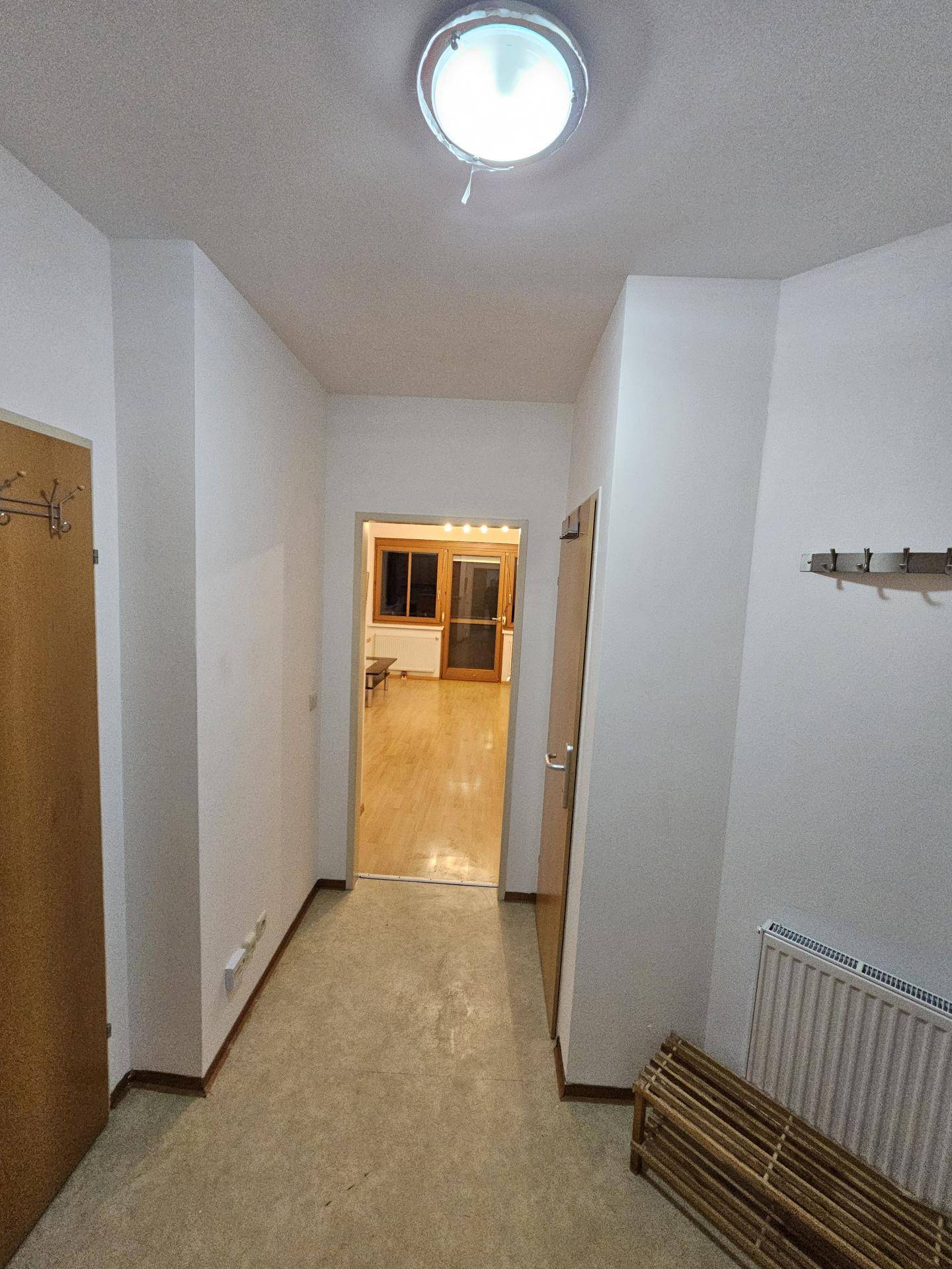 Langer Flur mit hellem Boden, der den Blick zum Wohnbereich freigibt.