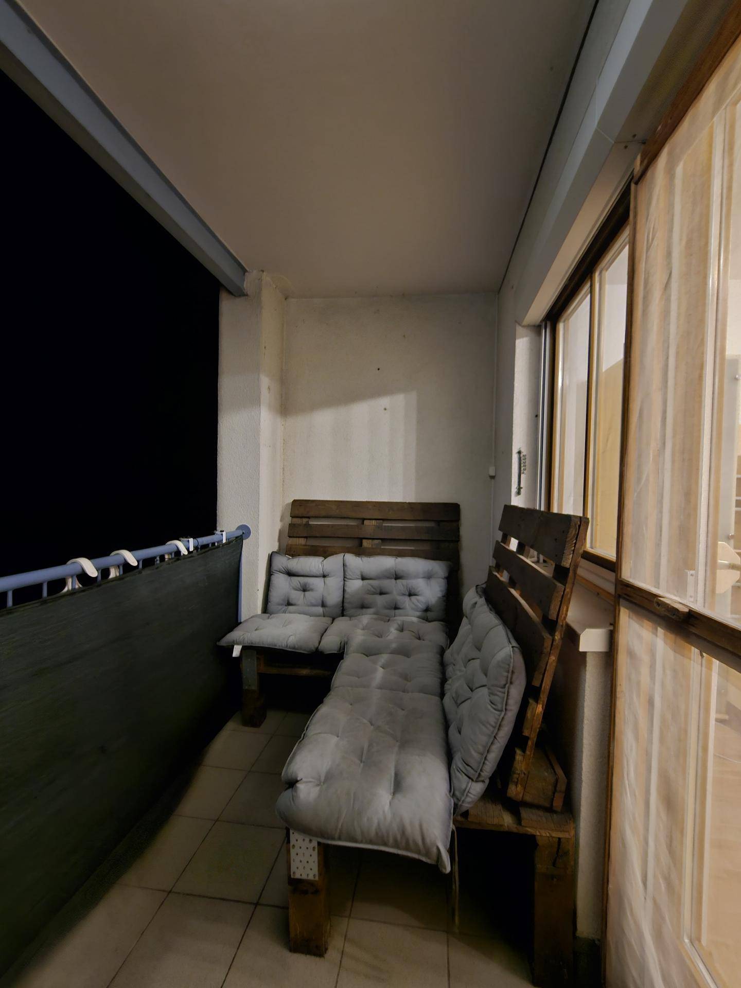 Gemütlicher Balkon bei Nacht mit bequemen Palettenmöbeln und Kissen.