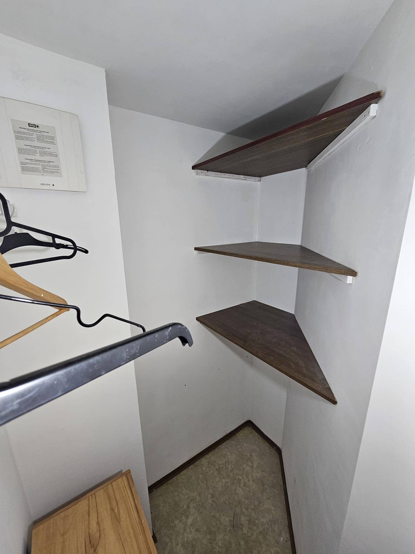 Abstellraum mit Eckregalen und Kleiderbügeln, bietet vielseitige Aufbewahrungsmöglichkeiten.