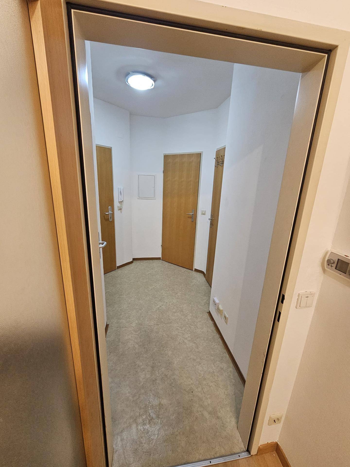 Heller Flur mit mehreren Türen und funktionalem Bodenbelag, der zu den Zimmern führt.