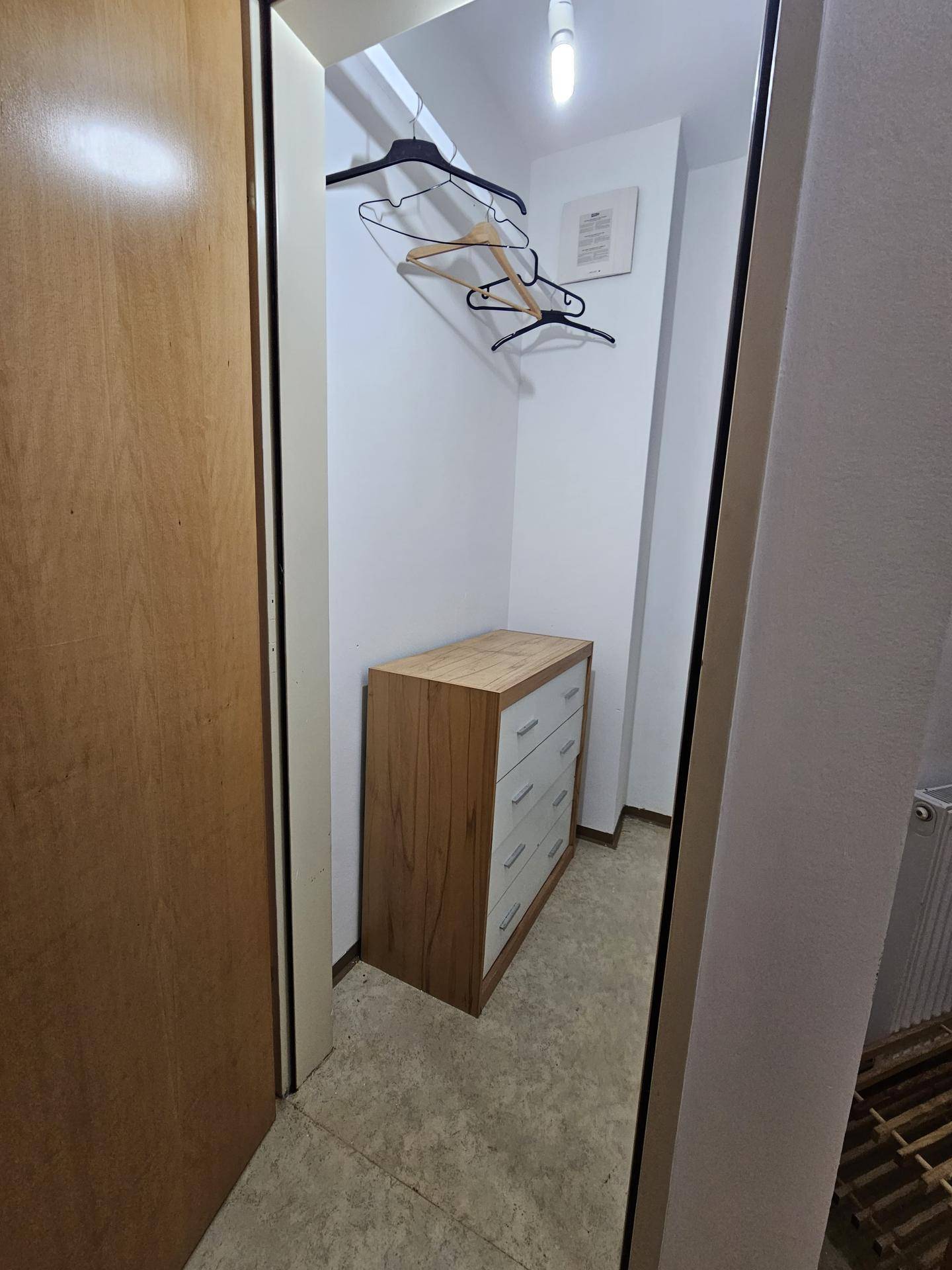Geräumiger Abstellraum mit Kommode und Kleiderstange, ideal für Kleidung und Haushaltsgegenstände.