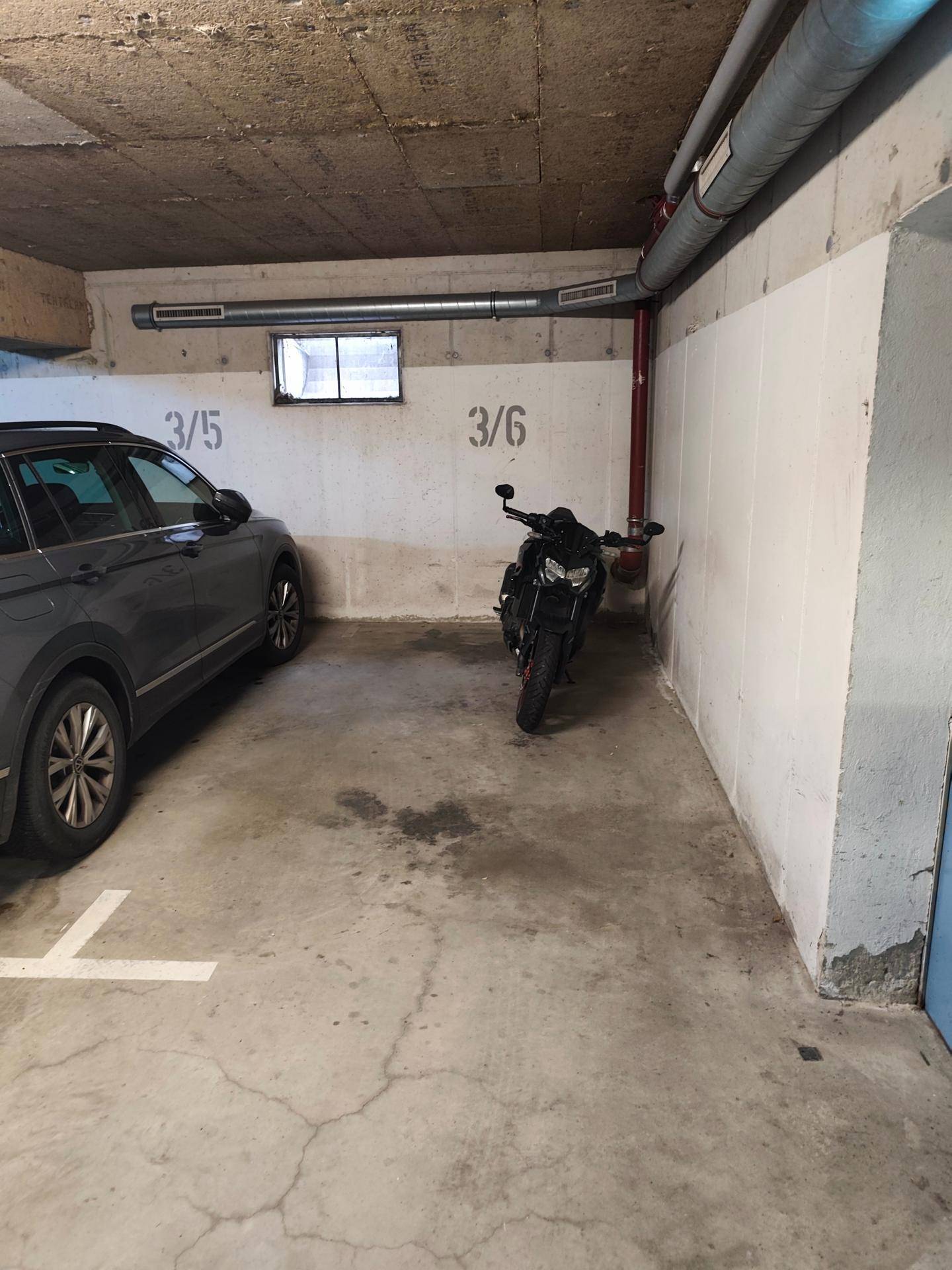 Tiefgarage mit Betonboden und markierten Stellplätzen für Fahrzeuge.