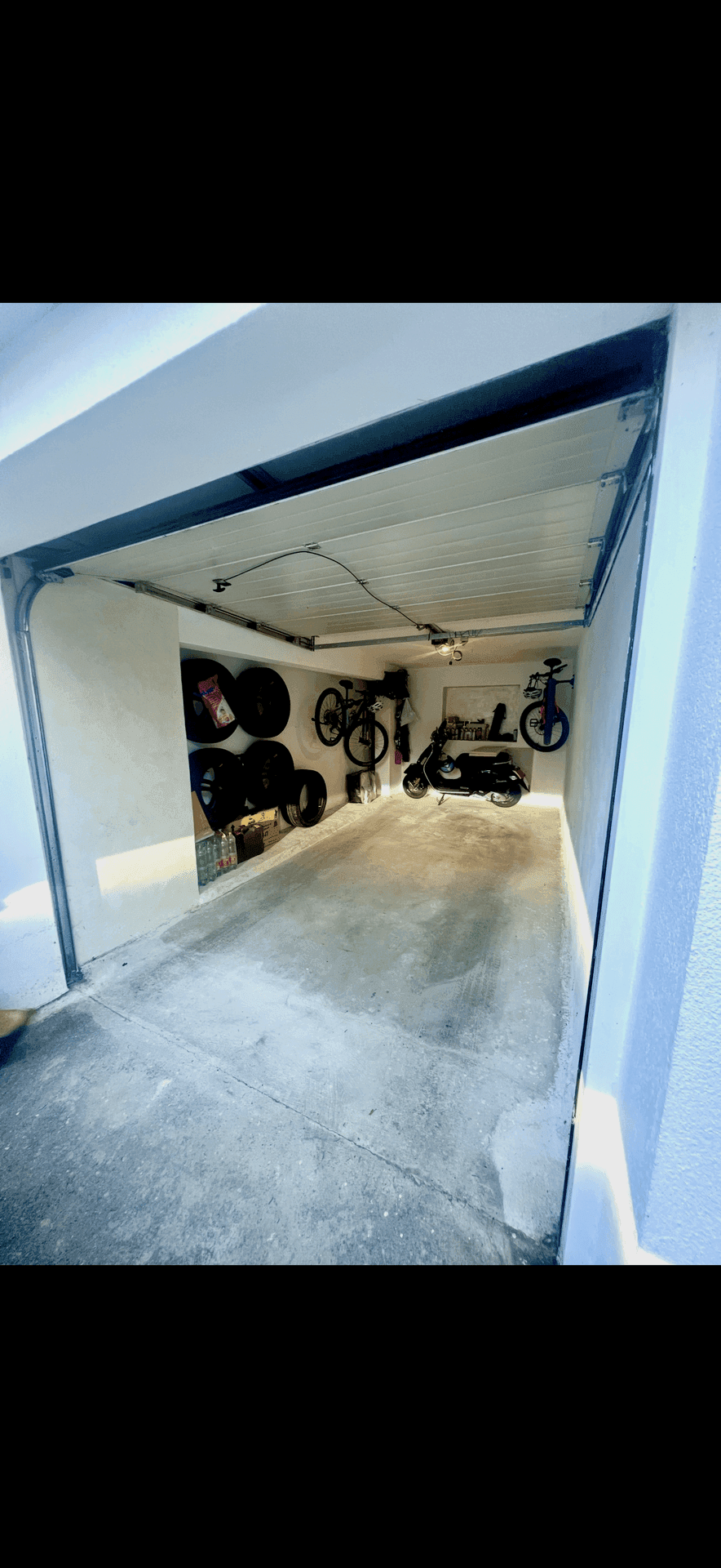 Einzelgarage mit Betonboden, genutzt zur Lagerung von Fahrrädern und Reifen.