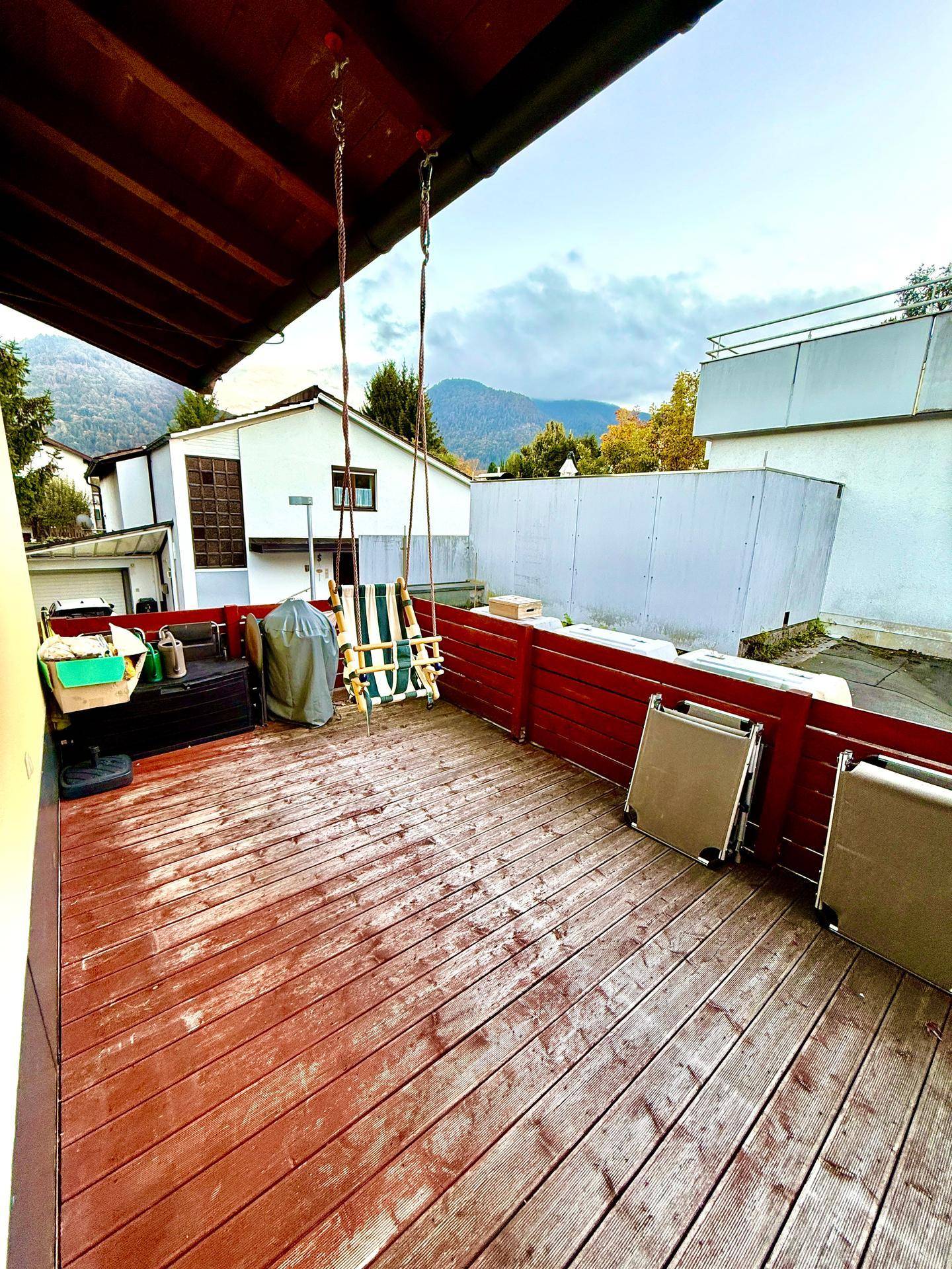 Geräumige Terrasse mit Schaukel und Blick auf die umliegende Landschaft und Berge.