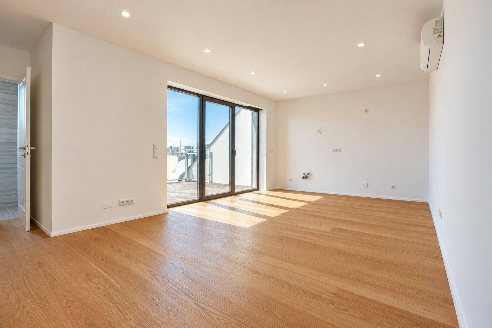 Lichtdurchfluteter Raum mit Holzboden, Zugang zur Terrasse und Klimaanlage.