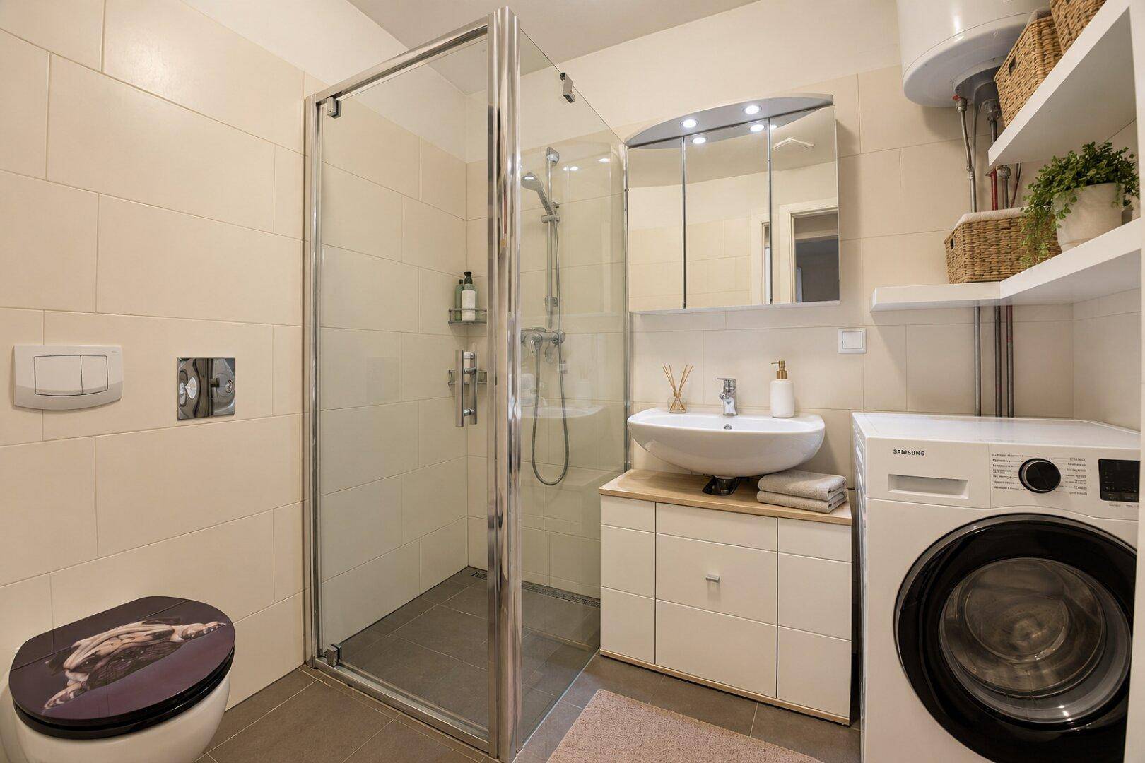 Modernes Badezimmer mit Dusche, Waschbecken und integrierter Waschmaschine.