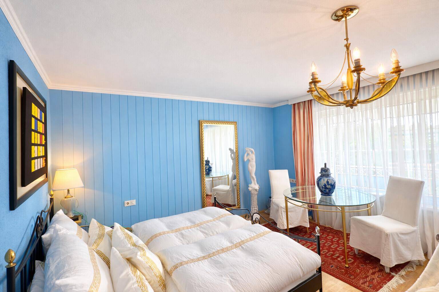 Helles Schlafzimmer mit blauen Holzpaneelen, eleganten Möbeln und viel Tageslicht.