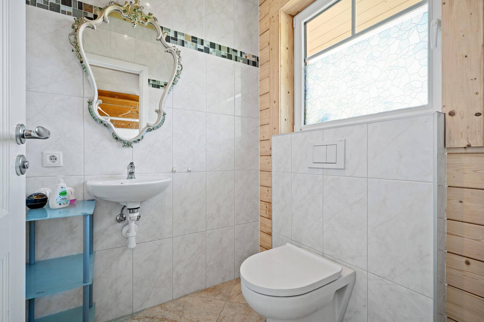 Kleines Gäste-WC mit Waschbecken, Toilette und weiß gefliesten Wänden.