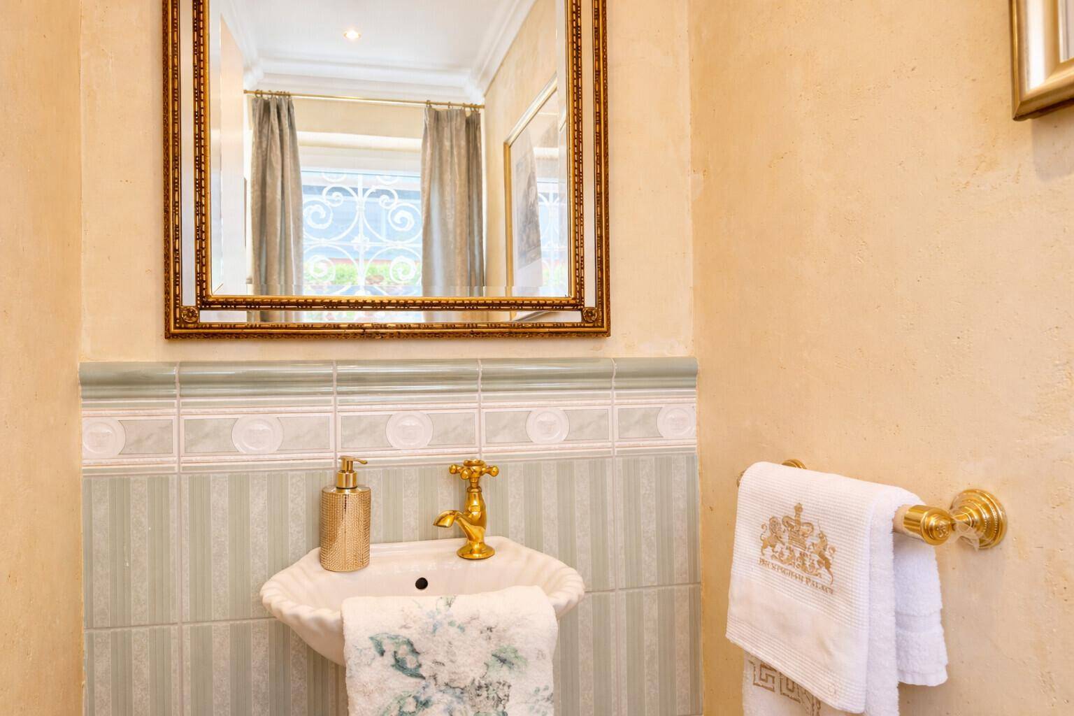 Stilvolle Gästetoilette mit goldenen Armaturen, kleinem Waschbecken und dekorativen Fliesen.