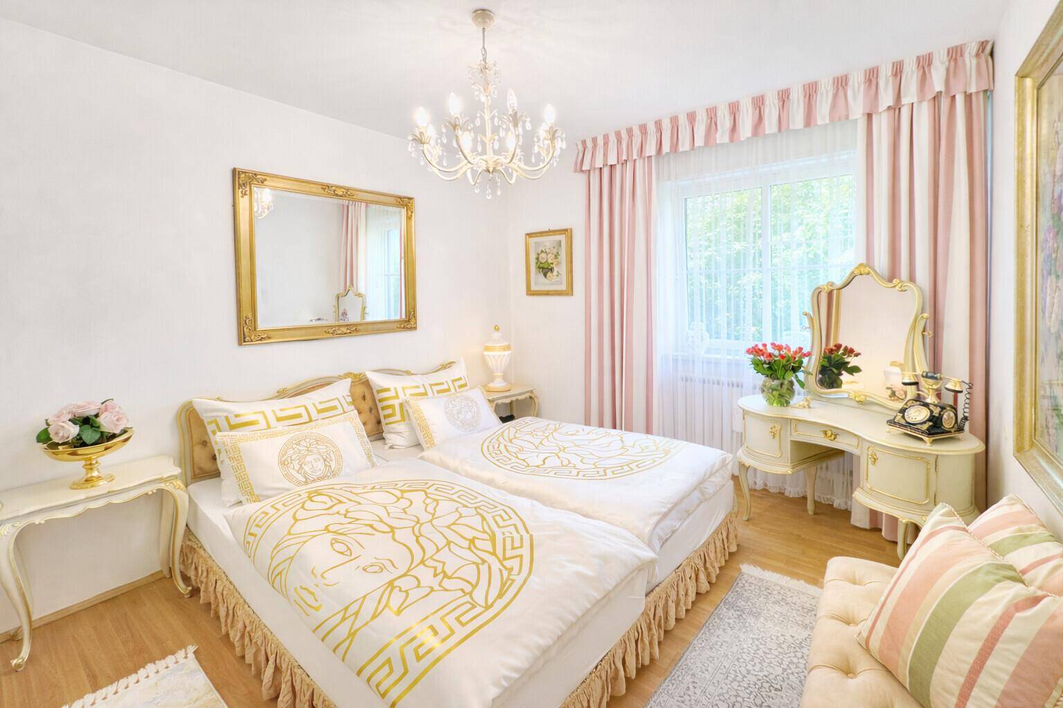 Charmantes Schlafzimmer mit weiß-rosa Einrichtung, Schminktisch und Kronleuchter.