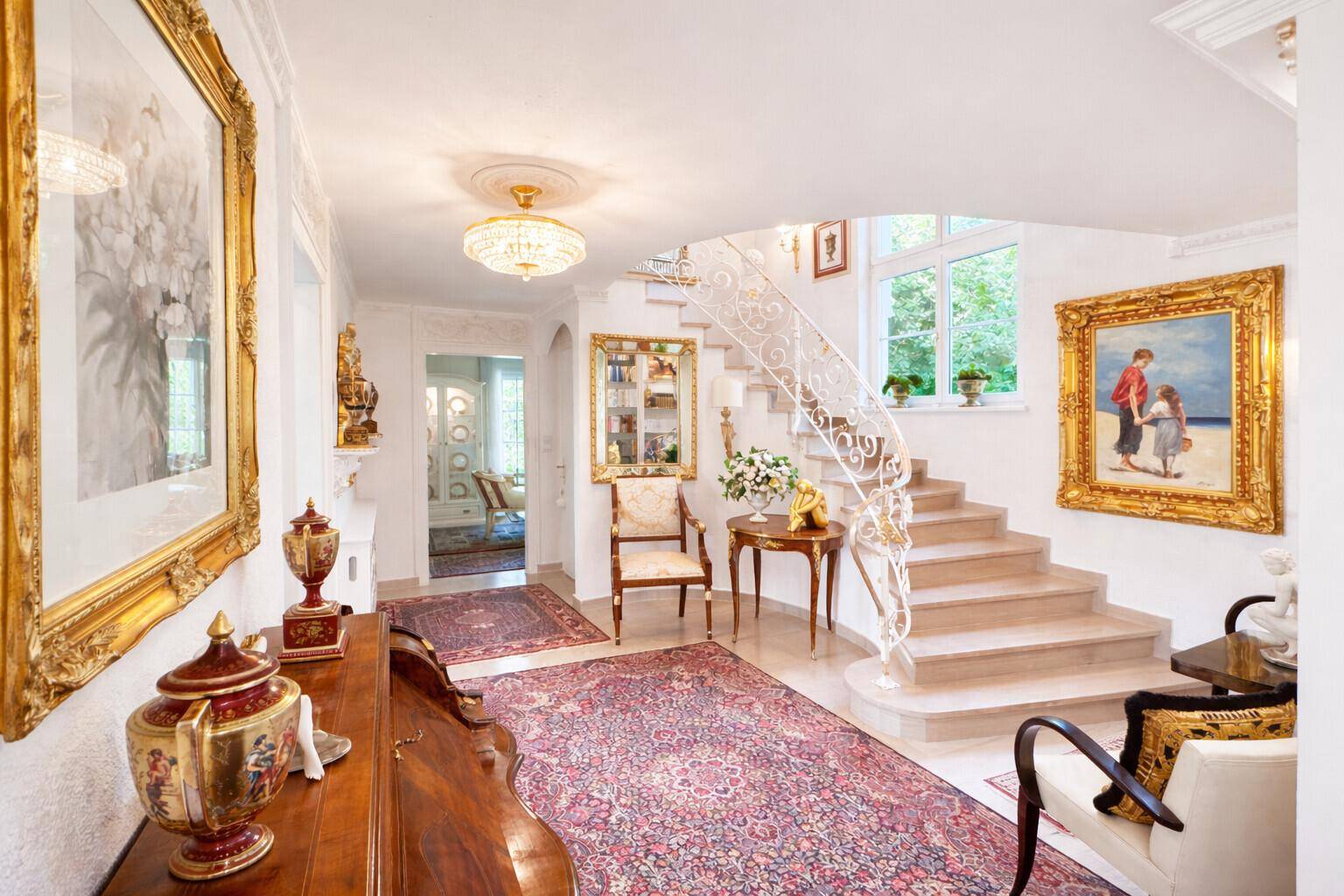 Repräsentative Eingangshalle mit eleganter Treppe, Marmorboden und opulenten Kunstwerken.