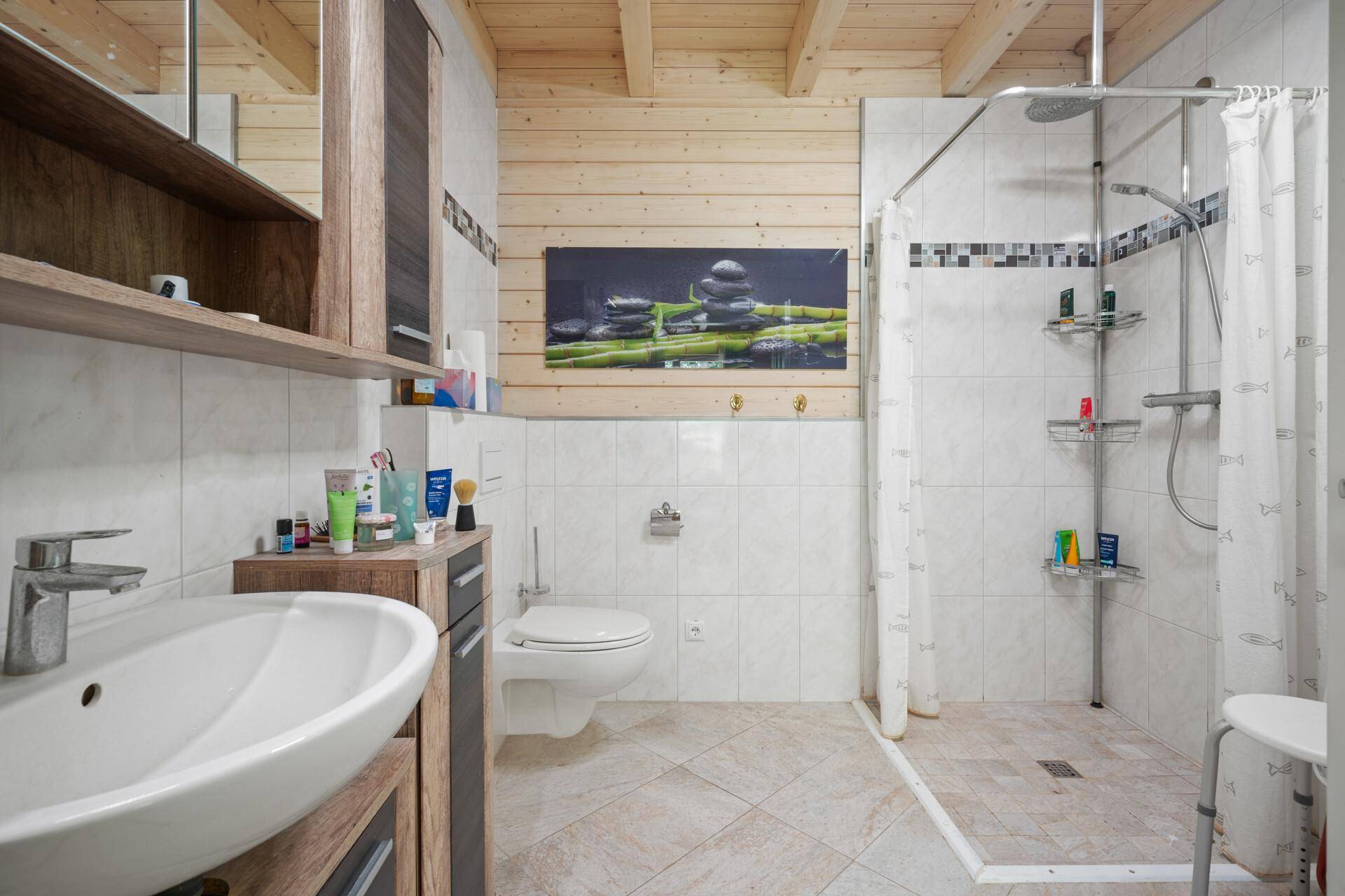 Modernes Badezimmer mit Dusche, Einzelwaschbecken und weißen Fliesen, Holzbalkendecke.
