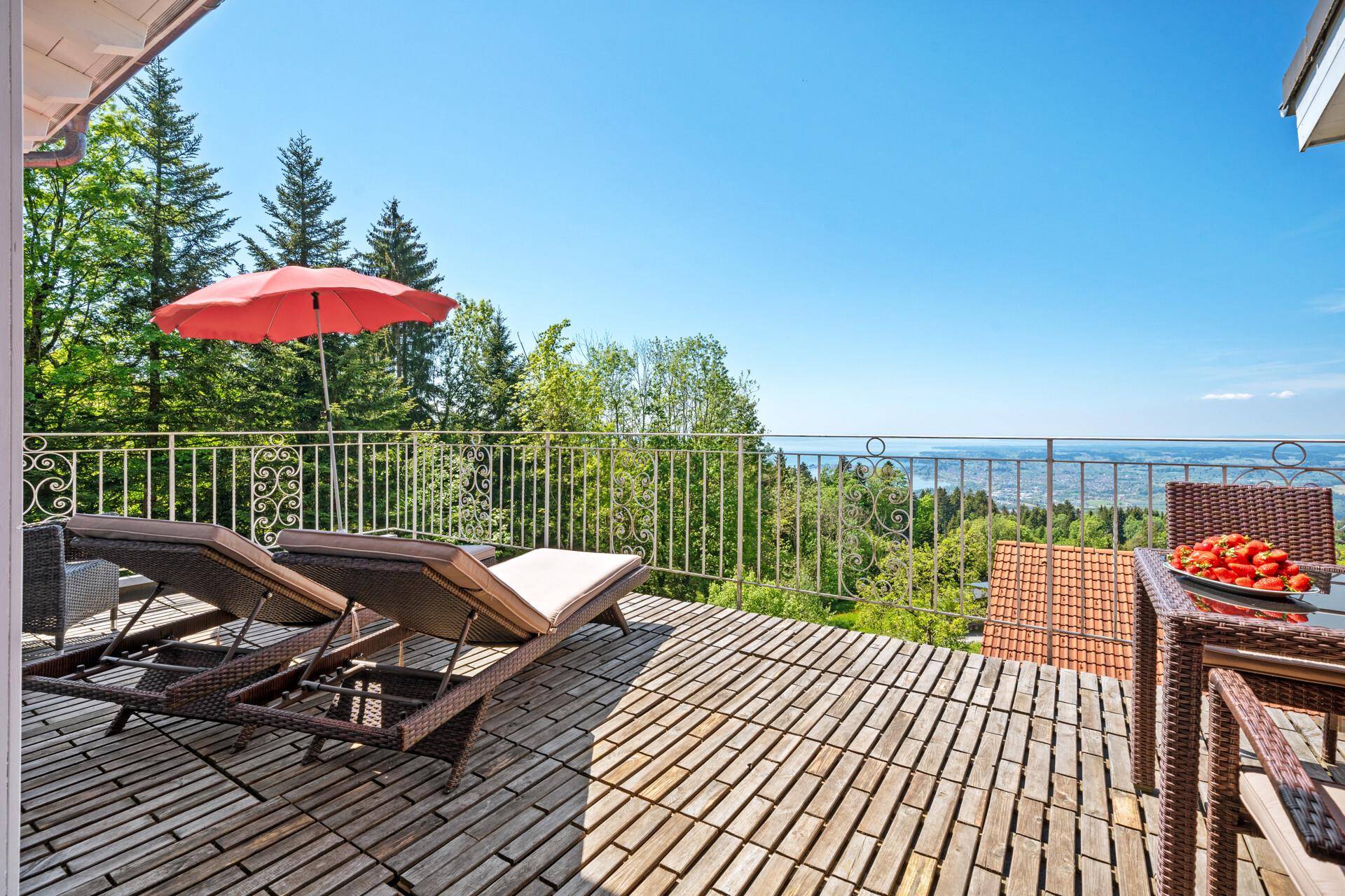 Sonnige Terrasse mit Liegestühlen und weitem Blick über den See und die Landschaft.