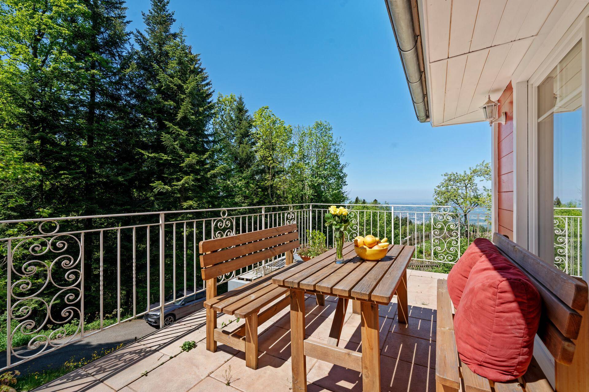 Geräumiger Balkon mit Holzsitzgruppe und weitem Blick über die grüne Landschaft.