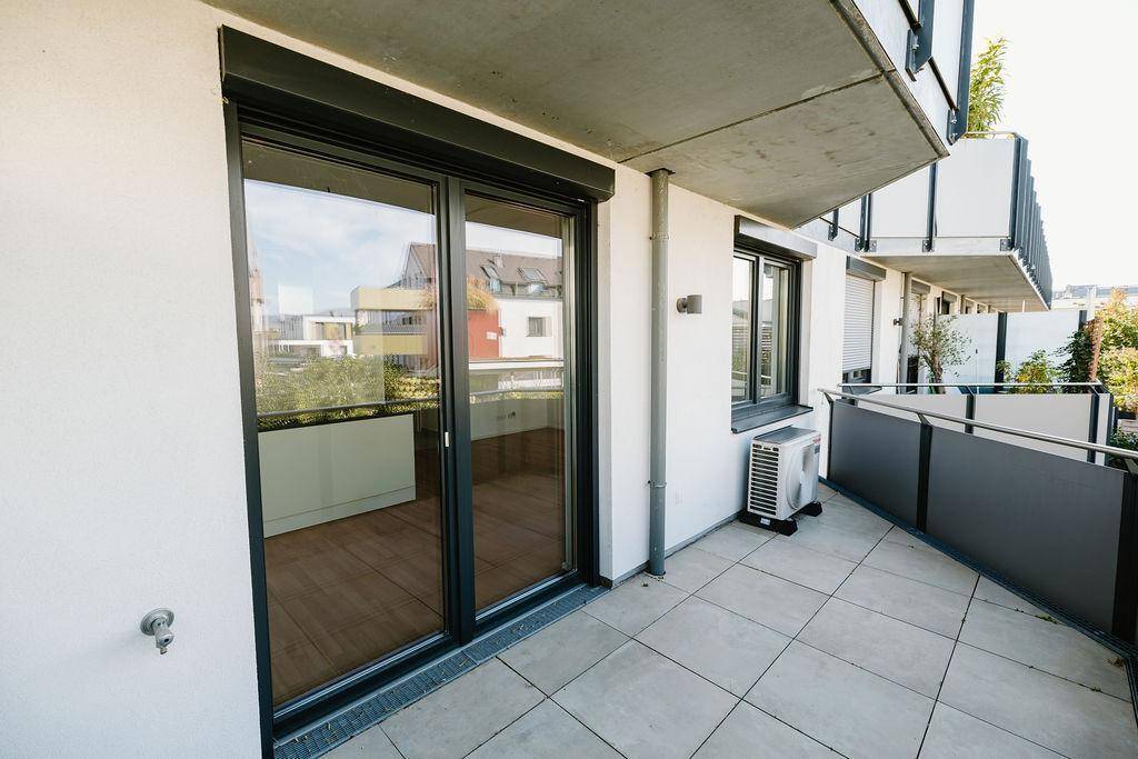 Geräumiger Balkon mit Schiebetüren, Fliesenboden und Klimaanlage, bietet einen Blick auf die Umgebung.