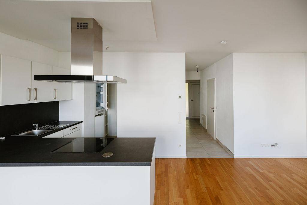 Moderne Einbauküche mit Induktionskochfeld, Backofen und Dunstabzugshaube, offen zum Wohnbereich.