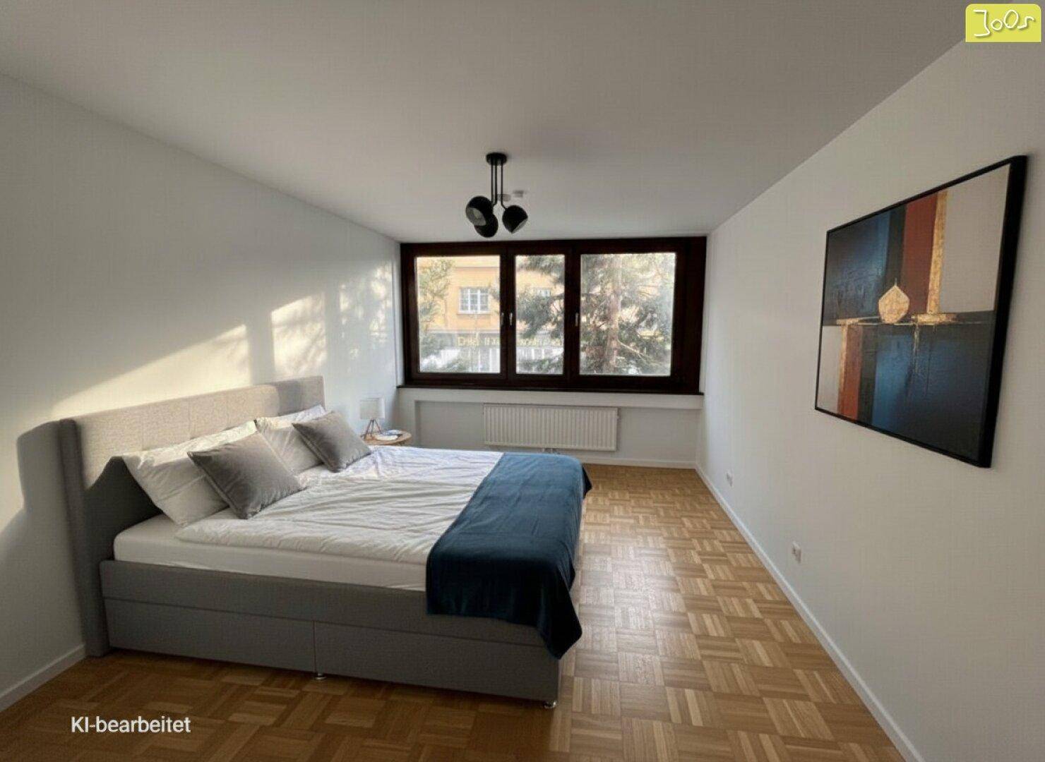 Schlafzimmer mit großem Bett, Parkettboden und breitem Fenster, bietet eine ruhige Atmosphäre.