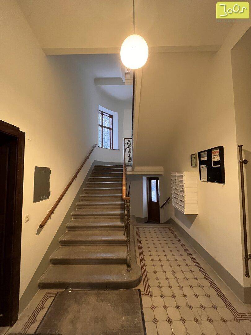 Historisches Treppenhaus mit originalen Fliesen und einer eleganten Treppe in einem Altbau.