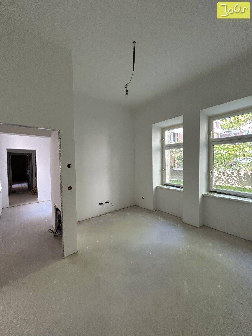 Geräumiger, unmöblierter Wohnraum mit zwei Fenstern und hellen Wänden, bereit zum Bezug.