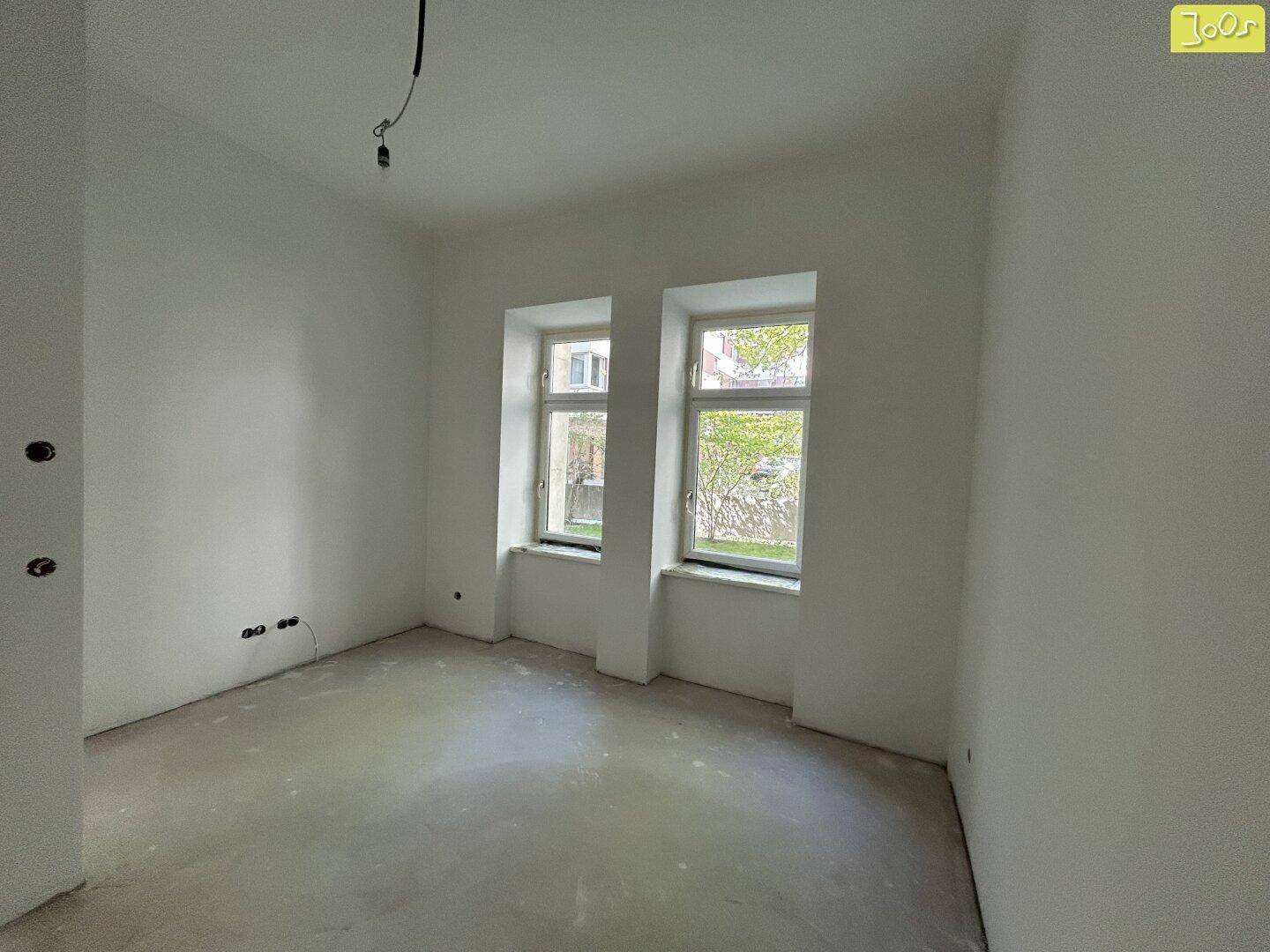 Heller, unmöblierter Raum mit zwei Fenstern und weiß gestrichenen Wänden, ideal als Schlafzimmer.