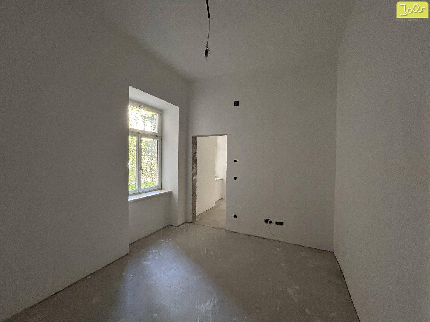 Heller, unmöblierter Raum mit einem Fenster und Türöffnung, bereit für individuelle Gestaltung.
