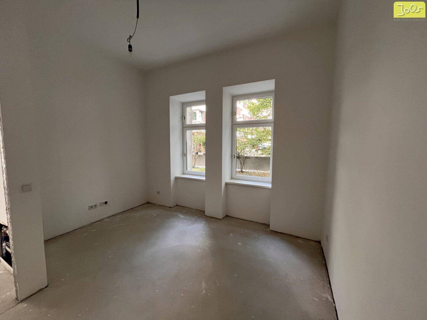 Heller, unmöblierter Raum mit zwei Fenstern und weiß gestrichenen Wänden, ideal als Schlafzimmer.