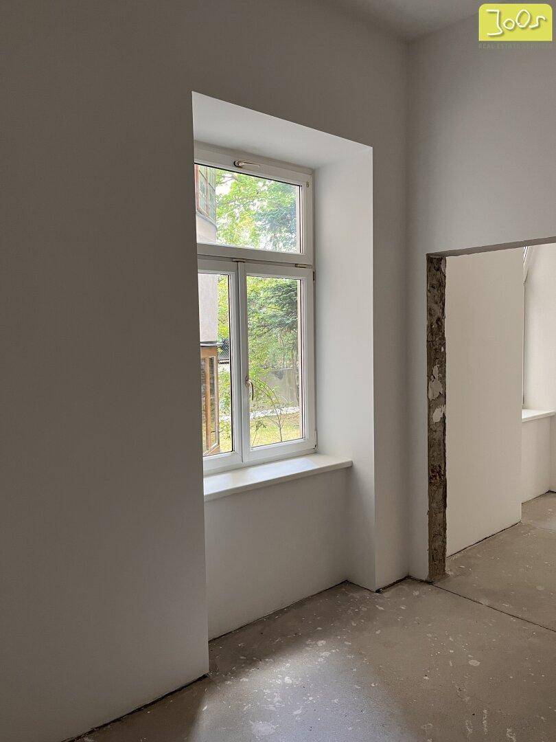 Unmöblierter Raum mit einem Fenster und Türöffnung, bereit für individuelle Gestaltung.
