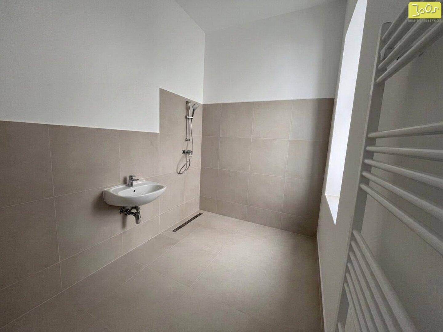 Modernes Badezimmer im Bau mit Duschbereich, Waschbecken und beheiztem Handtuchhalter.