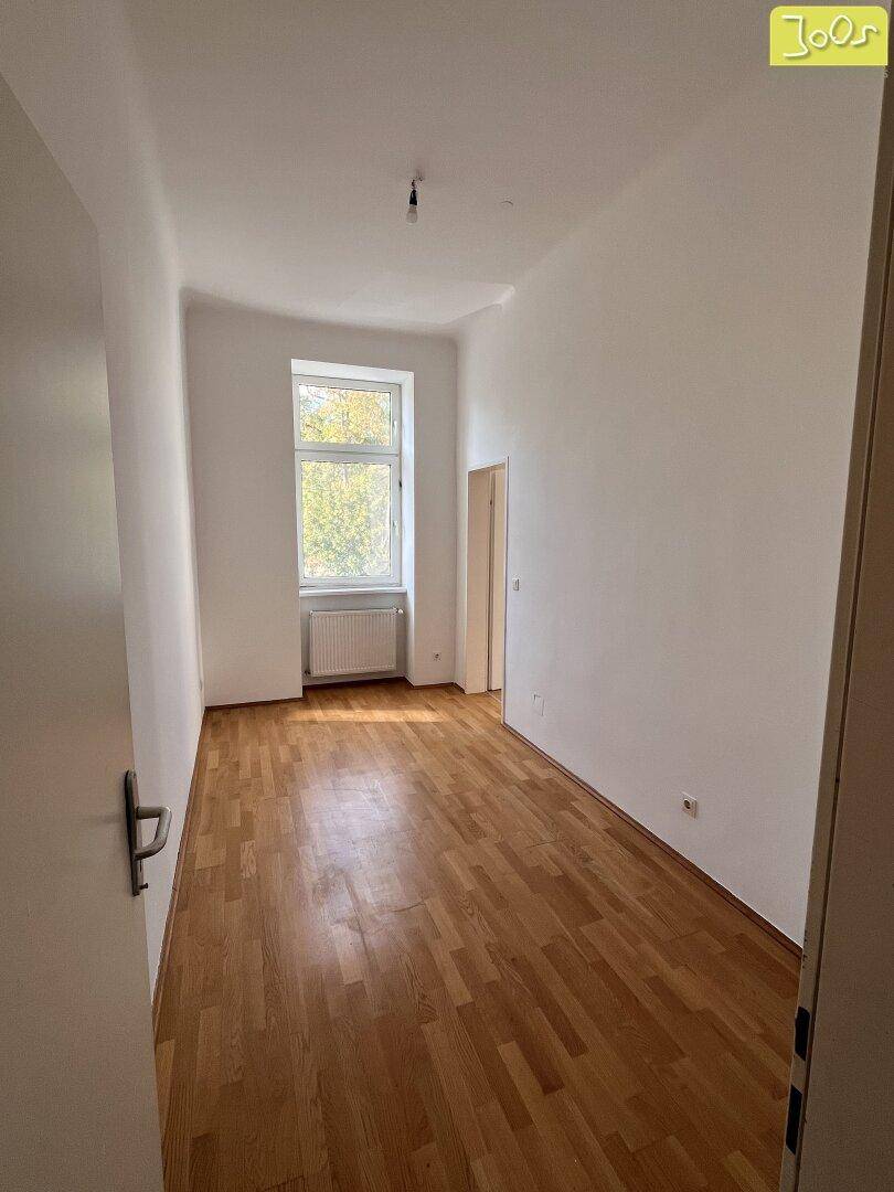 Langes, helles Zimmer mit Parkettboden und einem Fenster, ideal als Schlaf- oder Arbeitszimmer.