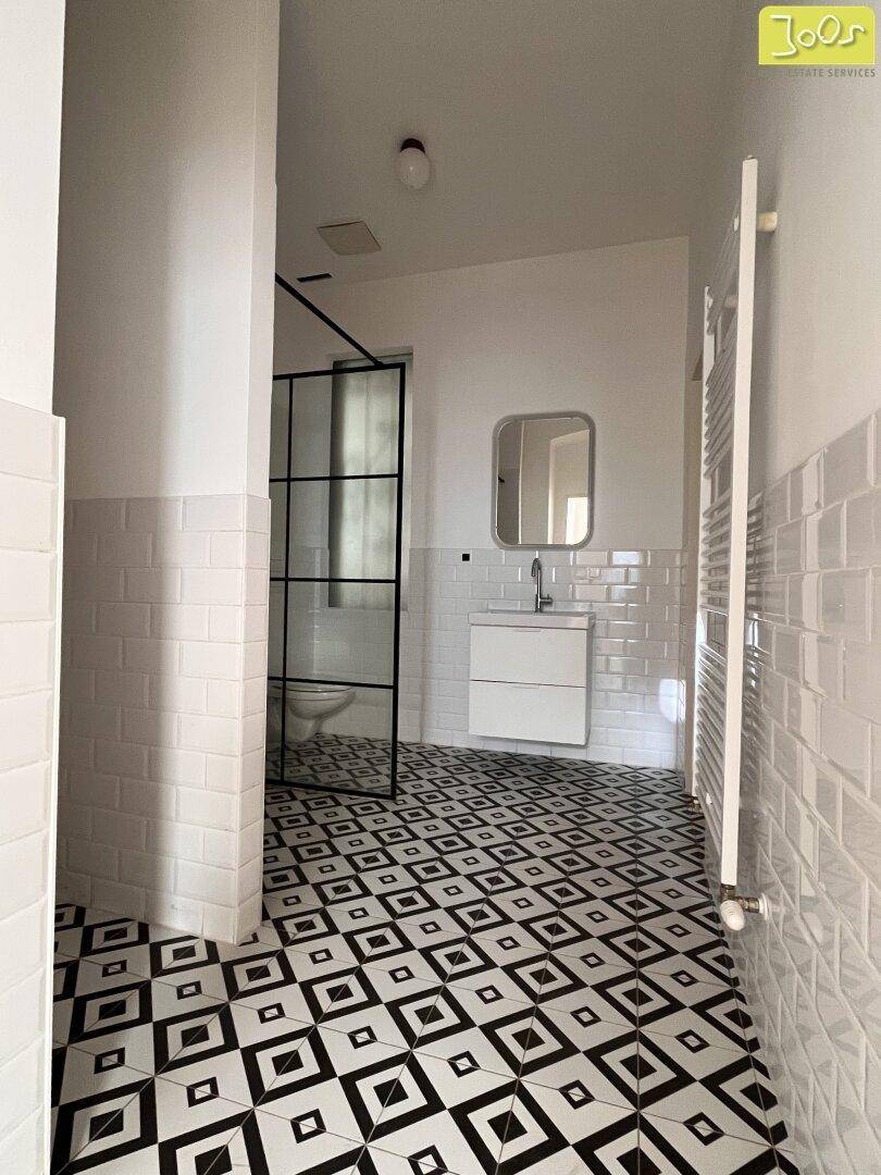 Modernes Badezimmer mit schwarz-weiß gemusterten Fliesen und begehbarer Dusche.