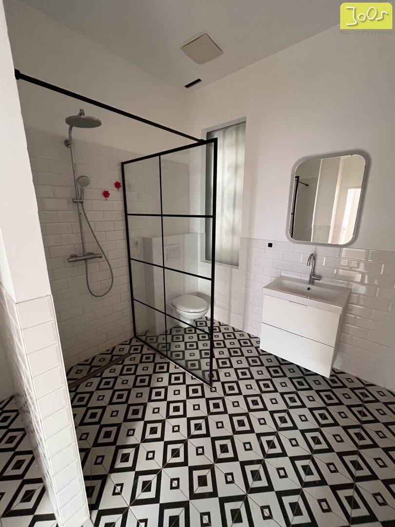 Stilvolles Badezimmer mit begehbarer Dusche, modernem Waschbecken und gemustertem Fliesenboden.
