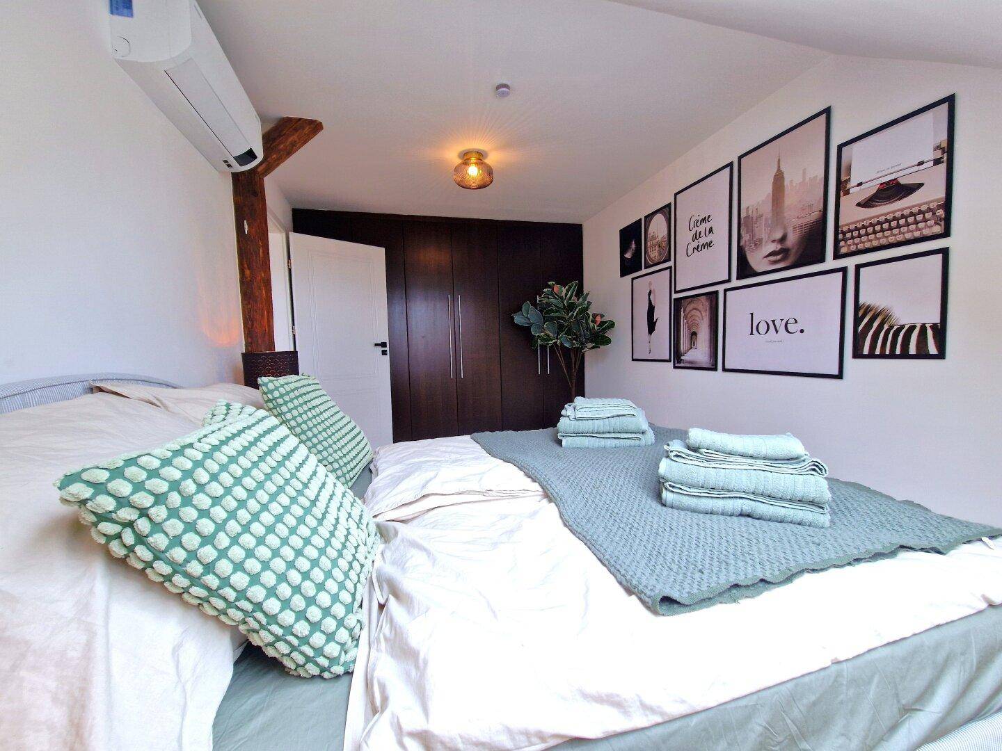 Modernes Schlafzimmer mit Einbauschränken, Holzbalken und stilvoller Wanddekoration.