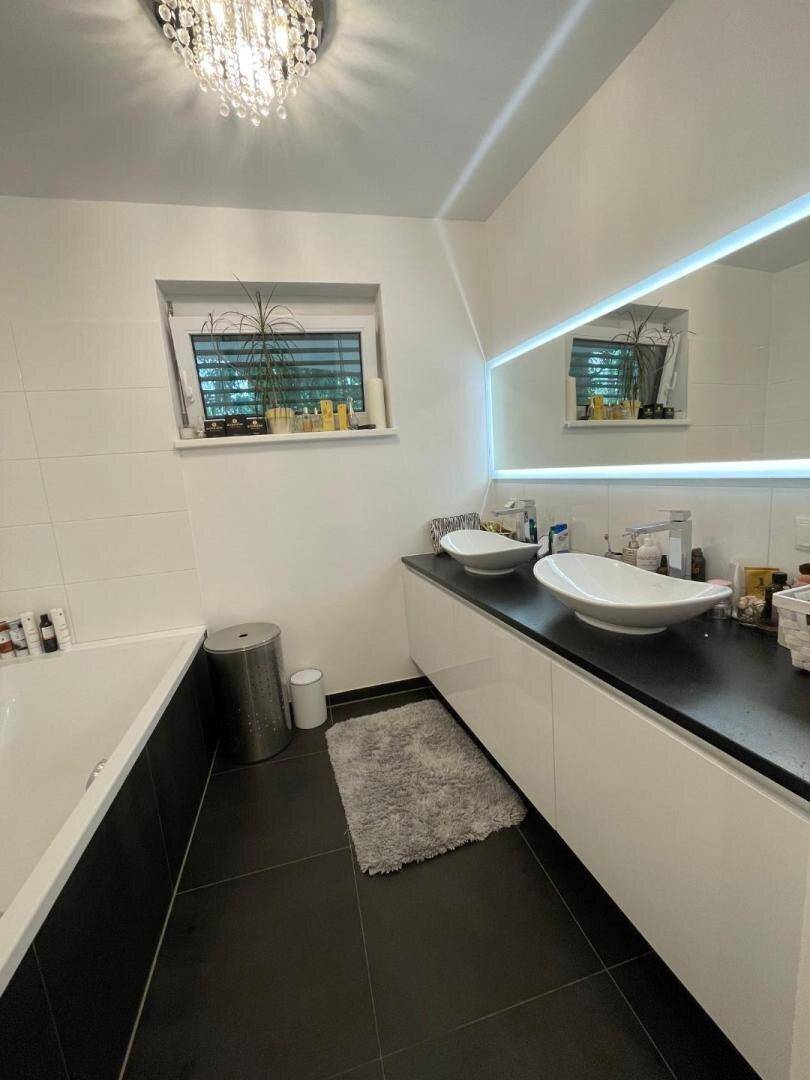 Helles Badezimmer mit Doppelwaschbecken, Badewanne und modernen Armaturen.