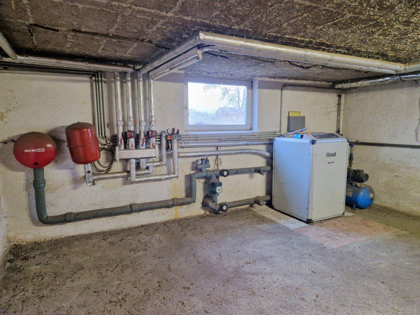 Heizungsraum im Keller mit moderner Heizungsanlage und sichtbaren Rohren.