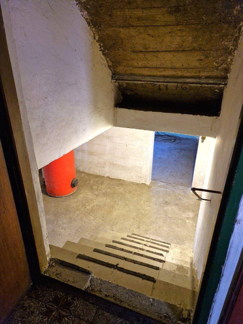 Treppenabgang in den Kellerbereich mit Betonboden und sichtbaren Installationen.