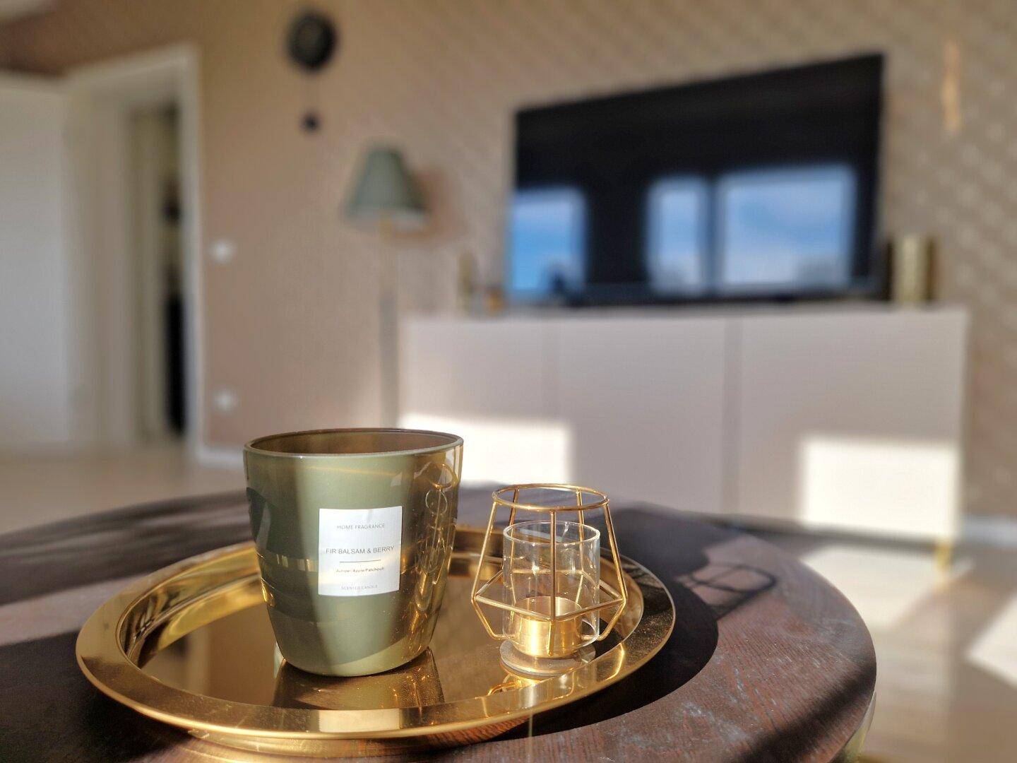 Dekorative Kerzen und Tablett auf einem Couchtisch im sonnigen Wohnzimmer.