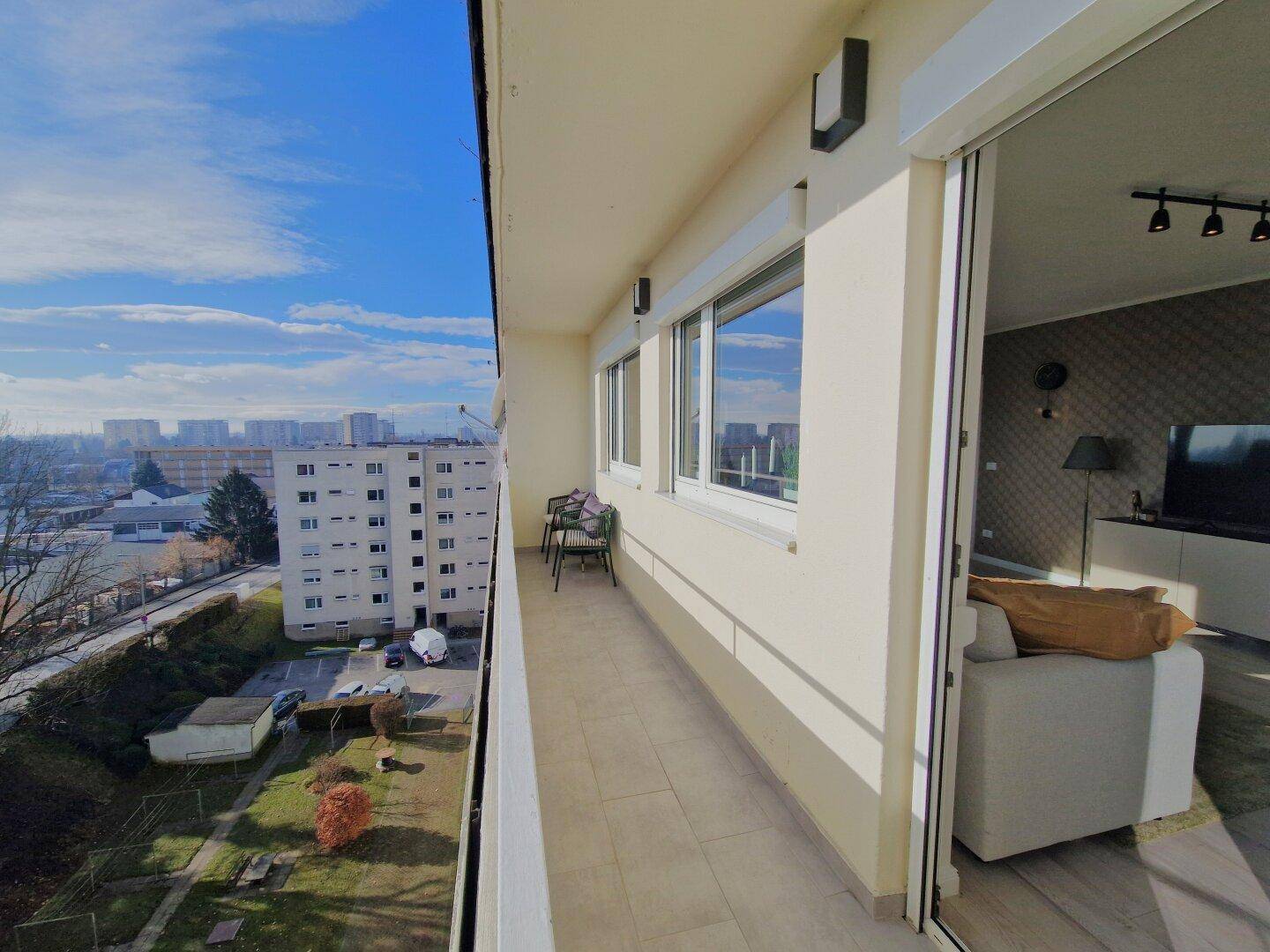 Langer Balkon mit Stadtblick und Zugang zum Wohnbereich, ideal für Entspannung.