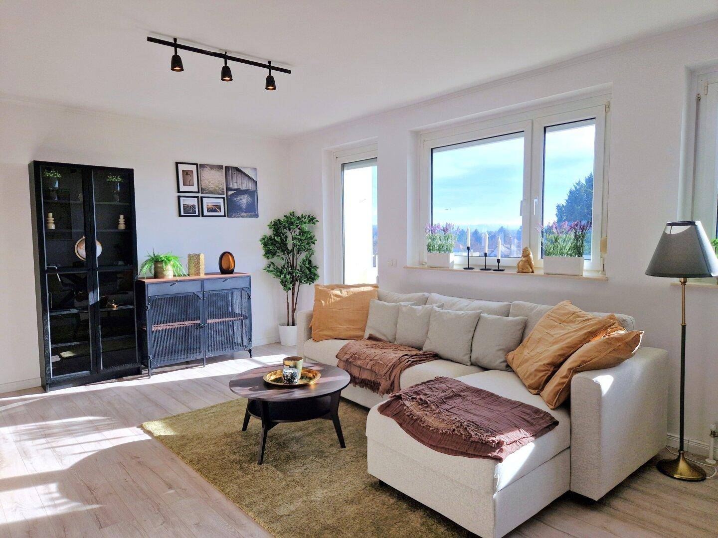 Geräumiges Wohnzimmer mit großer Eckcouch, vielen Fenstern und hellem Ambiente.