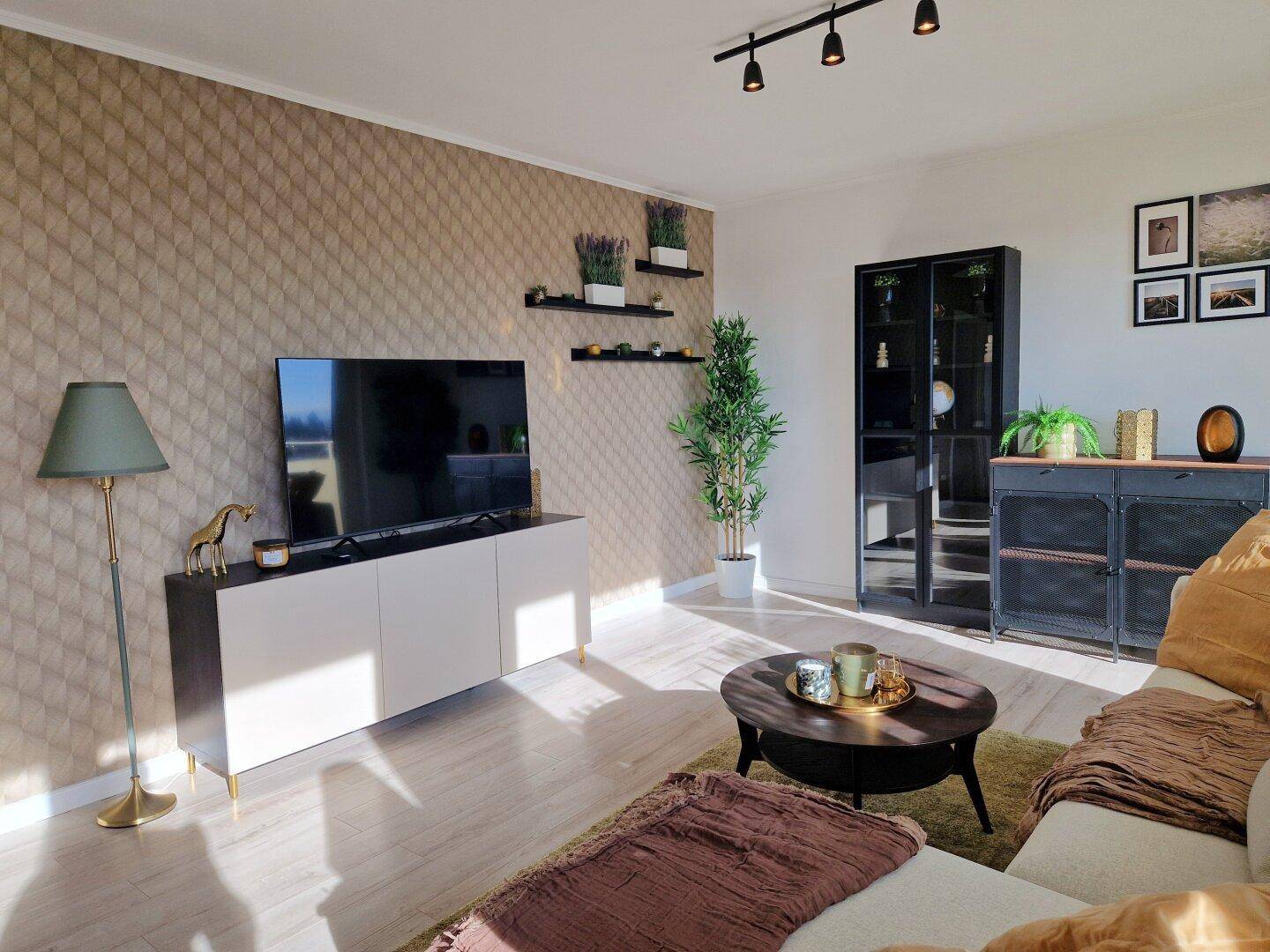 Modern eingerichtetes Wohnzimmer mit TV-Bereich, Sideboards und viel Tageslicht.