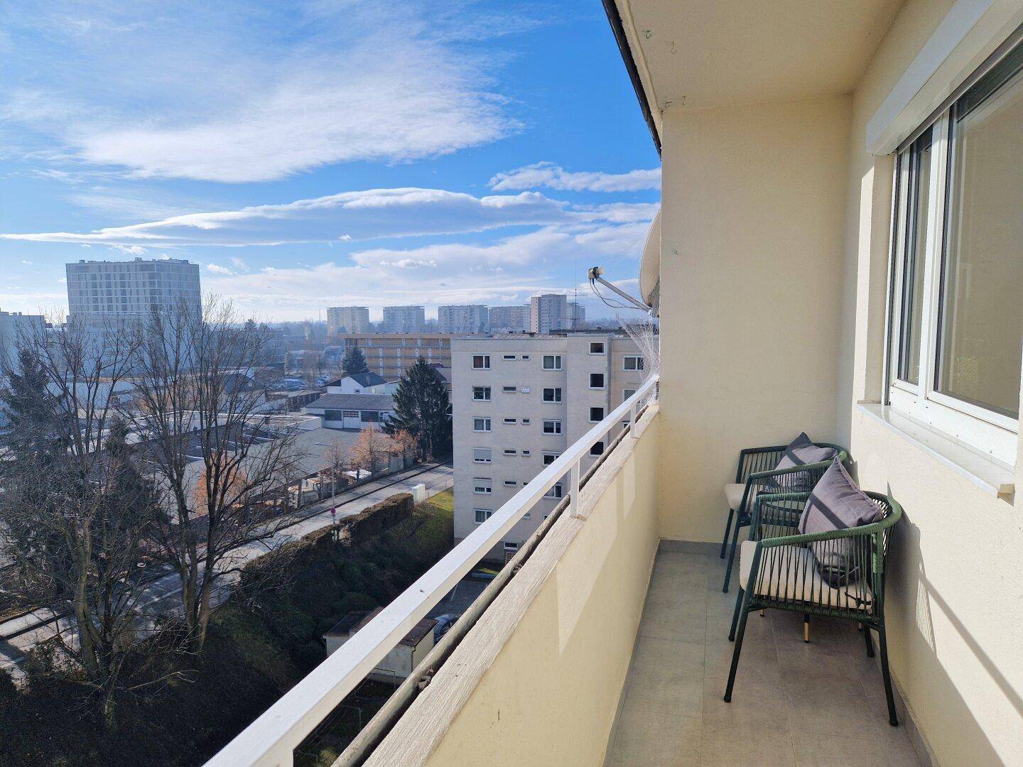 Balkon mit Weitblick über die Stadt und umliegende Gebäude, ausgestattet mit Stühlen.