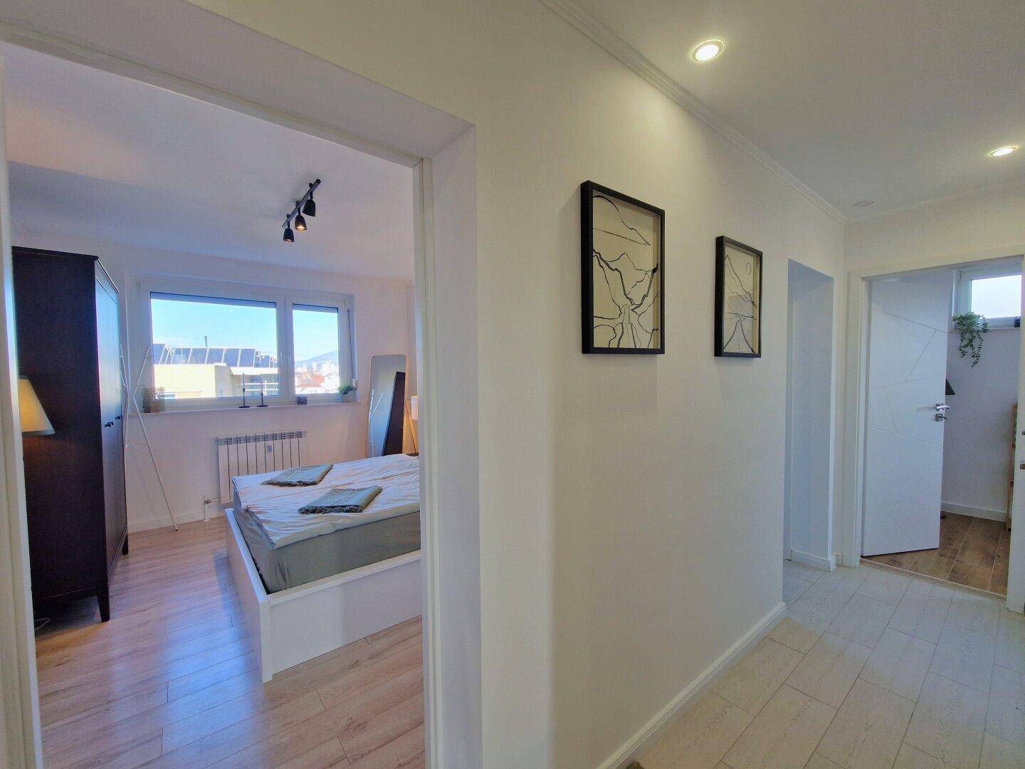 Heller Flur mit Zugang zu Schlafzimmer und Badezimmer, ausgestattet mit modernem Boden.