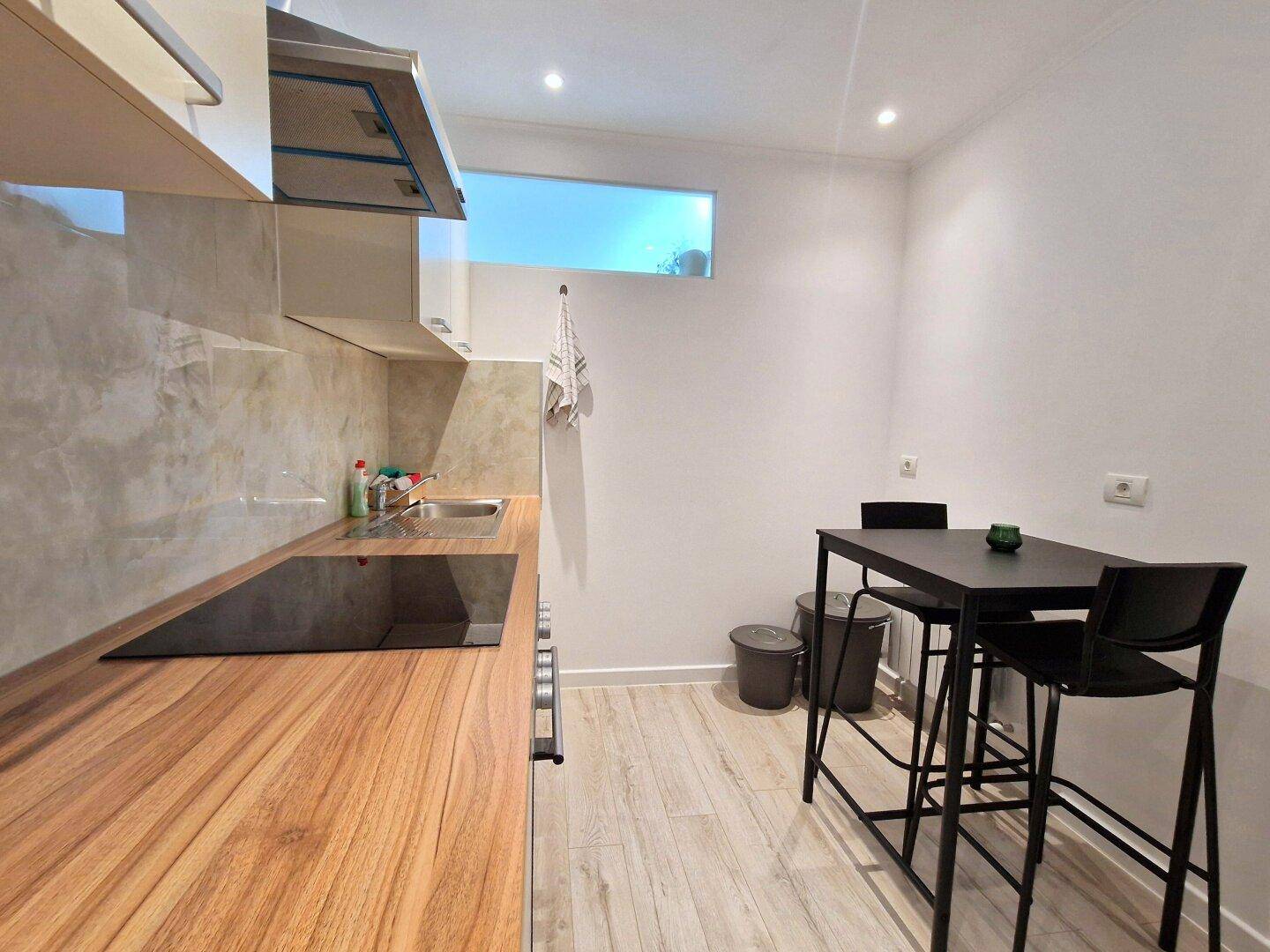 Moderne Küche mit Holzarbeitsplatte, Induktionskochfeld und Essbereich.