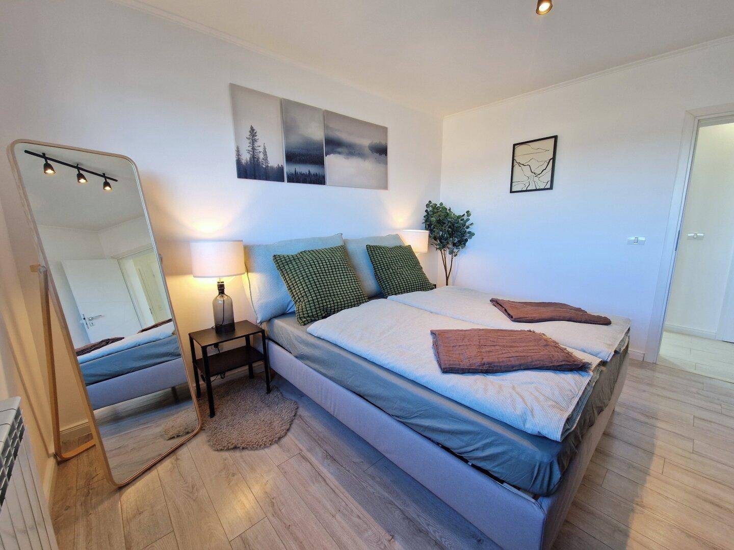 Gemütliches Schlafzimmer mit Doppelbett, Nachttisch und moderner Wanddekoration.