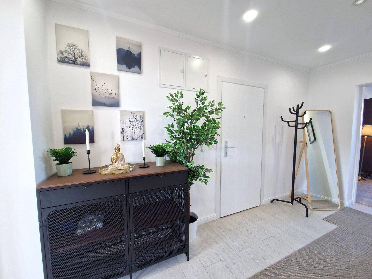 Eingangsbereich mit moderner Konsole, Spiegel, Garderobe und dekorativen Pflanzen.