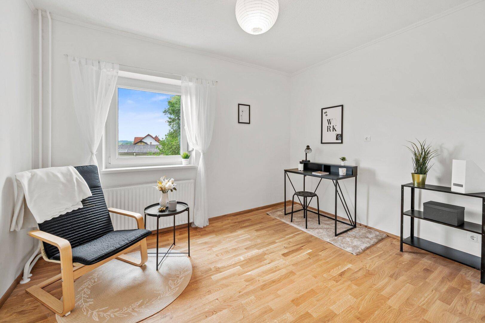 Helles Arbeitszimmer mit Holzboden, großem Fenster und moderner Einrichtung.