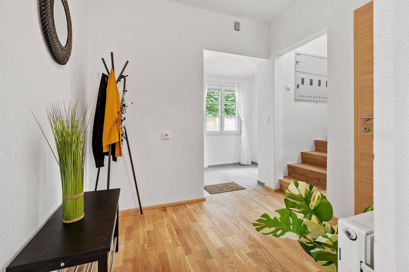Heller Flur mit Holzboden, Garderobe und Blick in den Eingangsbereich.