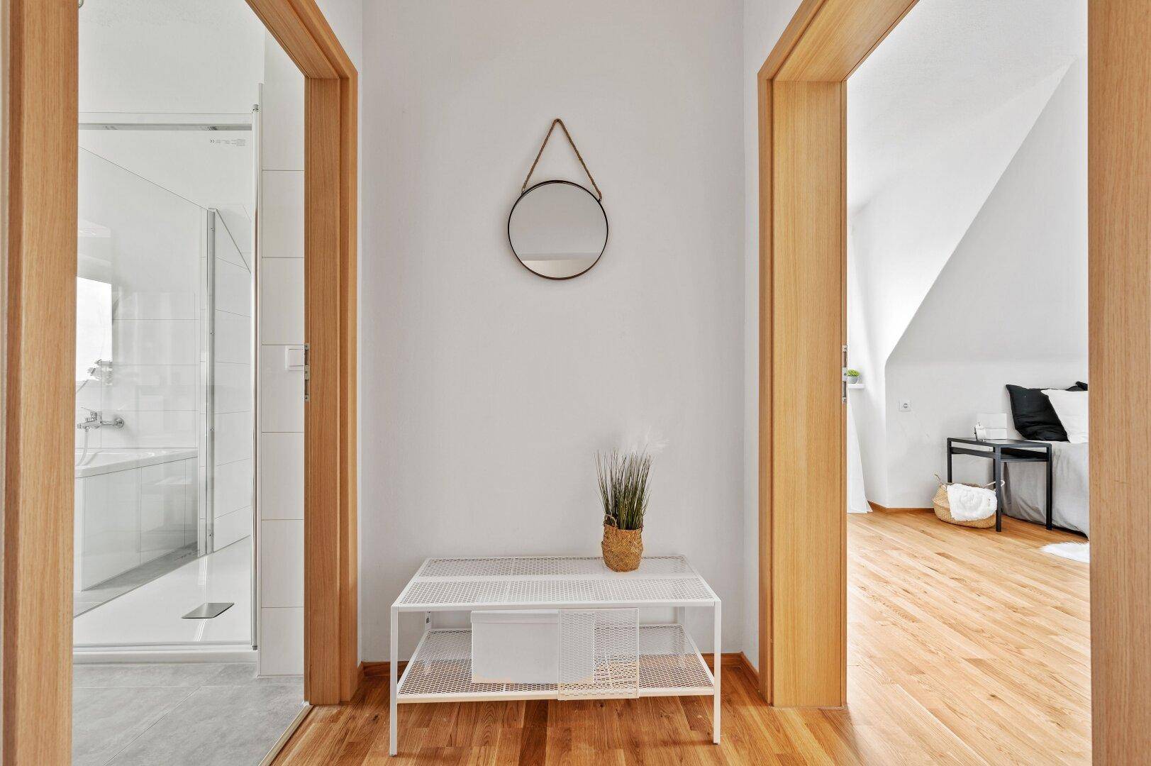 Heller Flur mit Zugang zu einem modernen Badezimmer und einem Schlafzimmer im Dachgeschoss.