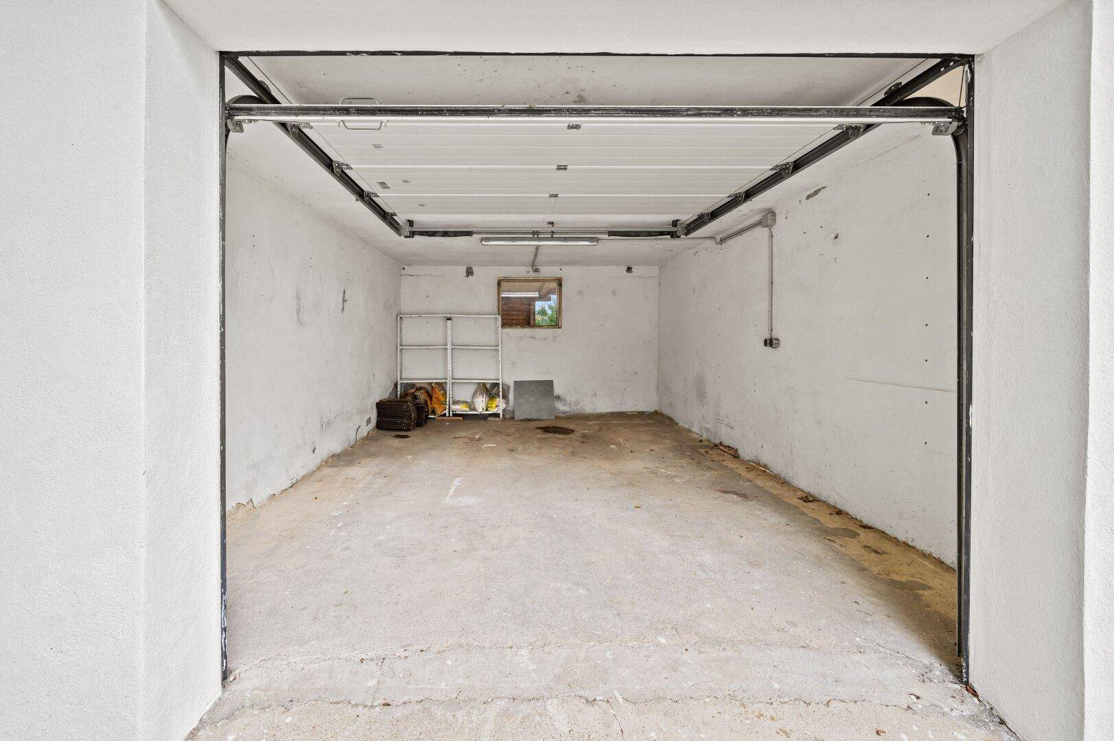 Geräumige Garage mit Betonboden und einem Fenster, ideal für Fahrzeuge oder Lagerung.